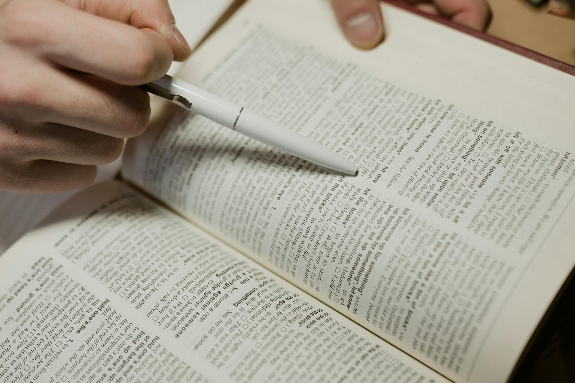 close up shot of a person pointing a pen on a book